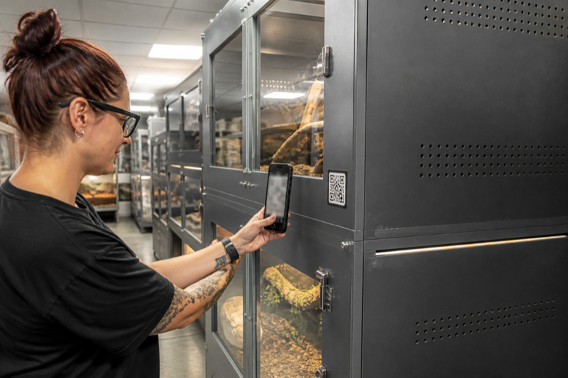 Keeper scanning a QR code on a reptile enclosure